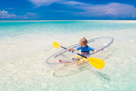 Kids kayaking in ocean. Children in kayak in tropical sea. Active vacation with young kid. Little boy and girl in canoe on beautiful beach. Holiday activity with child. Family water fun.の写真素材