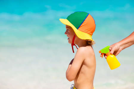 Mom applying sunscreen on child. Safe beach and sun tan fun. UV protection for young kid. Skin health care. Sun block spf cream and lotion for kids. Summer vacation with children.の写真素材