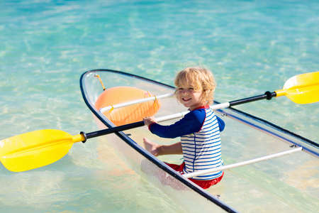 Kids kayaking in ocean. Children in kayak in tropical sea. Active vacation with young kid. Little boy and girl in canoe on beautiful beach. Holiday activity with child. Family water fun.の写真素材