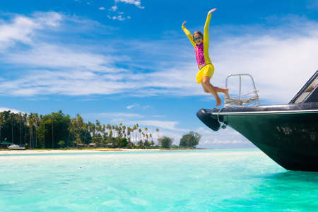 Kids jump into sea. Yacht vacation with child on exotic tropical island with crystal clear water. Beach and swim fun. Sailing and cruise with children. Summer holiday on boat. Little boy swimming.の写真素材