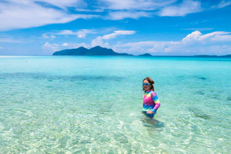 Kids playing on tropical beach. Children swim and play at sea on summer family vacation. Sand and water fun, sun protection for young child. Little boy running and jumping at ocean shore.の写真素材