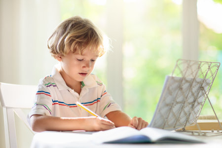 Child studying from home doing homework. Online remote learning. School kids with computer having...