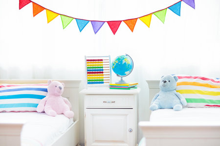 Bedroom for two kids. Interior for siblings nursery. White wooden bed at big window. Colorful rainbow bedding for boy and girl room. Nursery for brother and sister. Toy, abacus and globe as home decorの写真素材