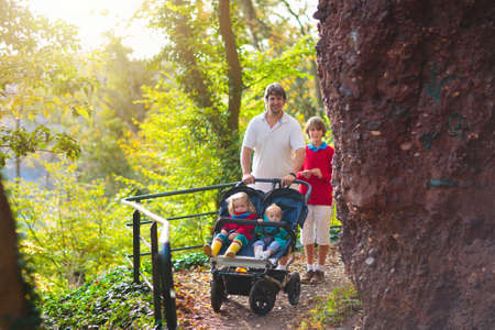 Man hiking with double pushchair. Father and kids on a walk. Healthy outdoor activity with little...