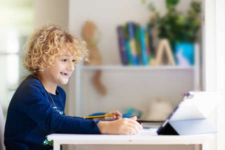 Online remote learning. School kids with computer having video conference chat with teacher and class group. Child studying from home. Homeschooling during quarantine and coronavirus outbreak.の写真素材