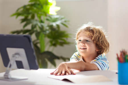 Online remote learning. School kids with computer having video conference chat with teacher and...