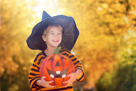 Kids trick or treat in Halloween costume. Children in colorful dress up with candy bucket on suburban street. Little boy and girl trick or treating with pumpkin lantern. Autumn holiday fun.の写真素材