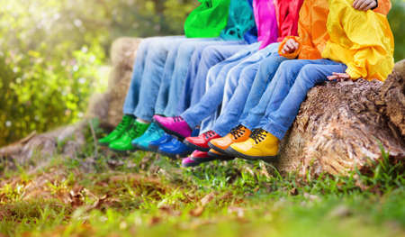 Colorful kids shoes. Children play outdoor. Hiking and trekking footwear for autumn park fun. Active child clothing and warm boots. Rain fall weather wear. Boy and girl fashion.の写真素材