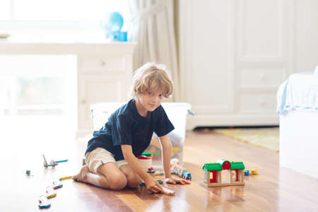Kids play with wooden railway. Child with toy train. Educational toys for young children. Little boy...