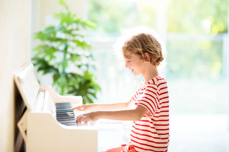 child playing piano. Kids play music. Classical education for children. art lesson. Little boy at white digital keyboard. Instrument for young student. Music class in school or at home.の写真素材