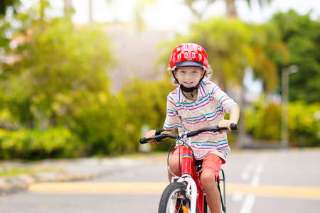 child riding bike. Kid on bicycle in sunny park. Little boy enjoying bike ride on his way to school on warm summer day. Preschooler learning to balance on bicycle in safe helmet. Sport for kids.の写真素材