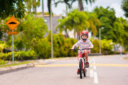 child riding bike. Kid on bicycle in sunny park. Little boy enjoying bike ride on his way to school on warm summer day. Preschooler learning to balance on bicycle in safe helmet. Sport for kids.の写真素材