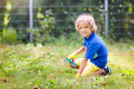 family gardening. Kids help in the garden. Little boy pulling weeds in sunny backyard. Child taking...