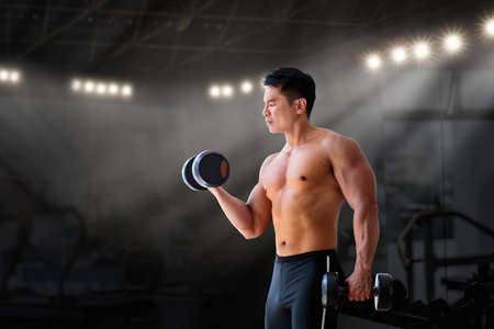 Man exercising in the gym. Asian bodybuilder lifting weights. Sport and healthy activity for young...
