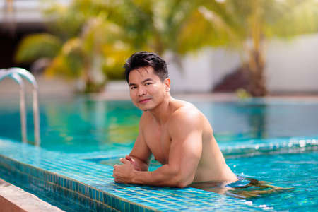 Young athlete man in swimming pool. swim exercise. Asian bodybuilder on tropical vacation. Healthy...