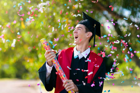 School or college graduation ceremony. Young man in academic regalia, gown and cap, celebration of successful diploma certificate. High school graduate in robe, stole and mortar board.の写真素材