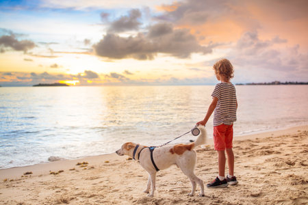 Child and dog playing on tropical beach at sunset. Little boy running with his puppy. Family summer vacation side. Sunrise on ocean. Travel with children and pets. Sea holiday with kids and animals.の写真素材