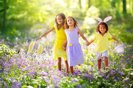 Easter egg hunt. Group of kids searching for colorful eggs. Children wear bunny ears. Boy and girl...