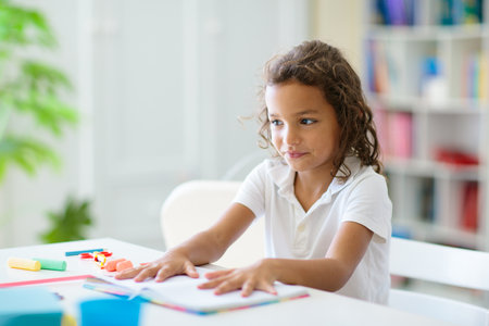 Kids go back to school. Interracial group of children of mixed age in the classroom. Students learn to read and write. Preschooler or kindergarten kid with teacher. Child learning letters with flash cardsの写真素材