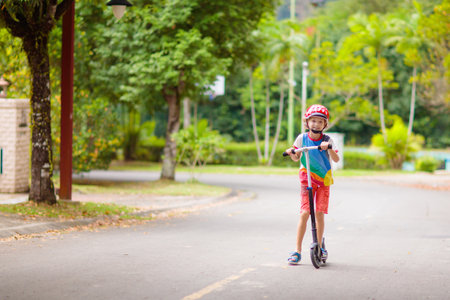 Little boy riding scooter. Kids ride kick board. Child playing on suburban street on sunny summer day. Safe helmet for kids. Healthy outdoor activity. Cute kid on his way to school.の写真素材