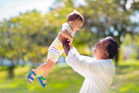 Father and son in sunny park. Loving family playing outdoor. Grandfather holding little boy high in the air. Senior man and adorable baby play and laugh. Happiness and love. happy fathers day.の写真素材