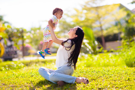 mother and son in sunny park. Loving Asian family playing outdoor. Mom holding little baby boy. Young woman and adorable child play and laugh. Happiness and love. Happy mother's day.の写真素材