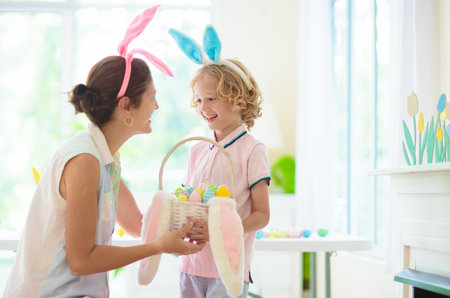 Mother and child color Easter eggs. Little boy with bunny ears and mom dye eggs. Easter egg hunt for...