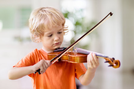 child playing violin. remote learning from home. Arts for kids. Little boy with musical instruments. video chat conference lesson. Online music training. creative children play song. classical educationの写真素材