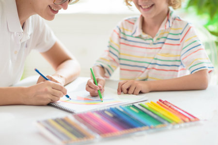 child drawing. School kid painting a picture. Little boy with colorful pencils doing homework in white sunny room. Kids draw and paint. Preschool art and crafts.の写真素材