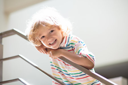 Little boy on stairs. Sunny staircase in new family home. Child climbing stairs. home interior....
