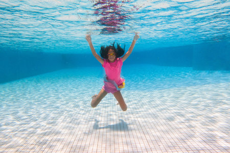 Little girl in swimming pool. Child learning to swim in outdoor pool of tropical resort. Water fun for baby and toddler. Travel with kids. Summer family vacation. Beach holiday with young kid.の写真素材