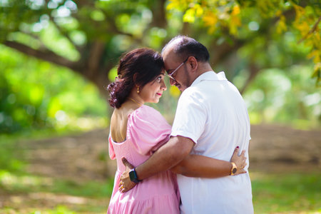 Young Indian couple in love. Man and woman walking in sunny summer park. Honeymoon in tropical resort. Husband and wife walk outdoor.の写真素材