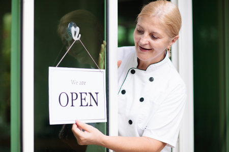 Cafe opening ceremony. Open sign on front door of restaurant or grocery store. Waiter in apron...