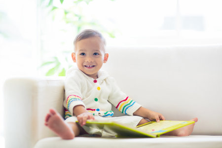 Baby boy reading a book. Kids read. Adorable Asian child holding a fun colorful preschool book. Early development and education. Educational toys for infant children. Toddler kid learning letters.の写真素材