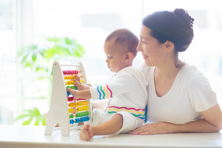 Baby boy and mother playing with wooden abacus. Kids learn to count. Adorable Asian child learning numbers. Early development and education. Educational toys for infant children. Toddler kid at home.の写真素材