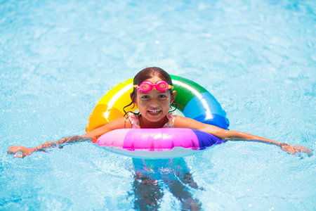 Child in swimming pool floating on toy ring. Kids swim. Colorful rainbow float for young kids....