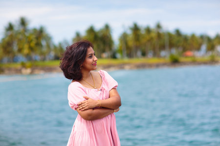 Young woman walking in yacht club. Indian female tourist in tropical resort. Summer beach vacation on exotic island. Beautiful girl in pink dress relaxing outdoor.の写真素材