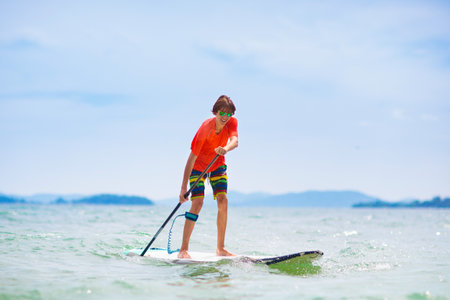 Young man standing up paddle board. Water fun and beach sport. Healthy outdoor sports for summer...