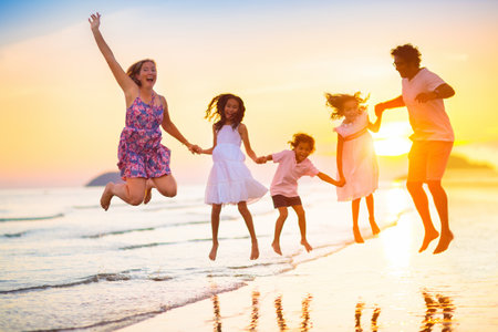 Family with kids walking on tropical beach at sunset. Cute little kids running with parents. Travel with kid. Summer vacation on seashore. Family holidays with children. water sports fun.の写真素材