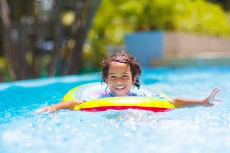 Child in swimming pool floating on toy ring. Kids swim. Colorful rainbow float for young kids....