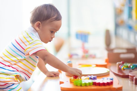 Adorable Asian baby boy in kindergarten or daycare. Child playing with colorful educational toys in preschool. Kids play indoor playground. Early education and child care.の写真素材