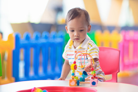 Adorable Asian baby boy in kindergarten or daycare. Child playing with colorful educational toys in preschool. Kids play indoor playground. Early education and child care.の写真素材