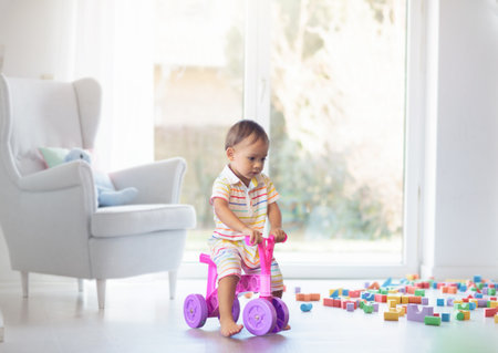 Adorable Asian baby boy on little push bike in kindergarten or daycare. Child playing with colorful educational toys in preschool. Kids play indoor playground. Early education and child care.の写真素材