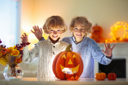 Family carving pumpkin for Halloween celebration. Mother and child cutting jack o lantern for traditional trick or treat decoration. Kids decorate home. Children carve pumpkin. Spooky Halloween fun.の写真素材