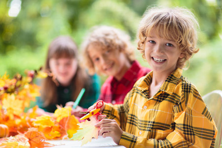 autumn home decoration. Fall arts and crafts. Family decorating house with colorful maple leaves banner. Thanksgiving or Halloween celebration sunny garden. Child with fall leaf.の写真素材