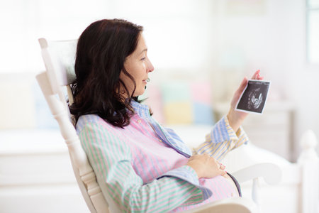 Pregnant woman at home. Young expecting mother in white bedroom. Healthy pregnancy. Female looking...
