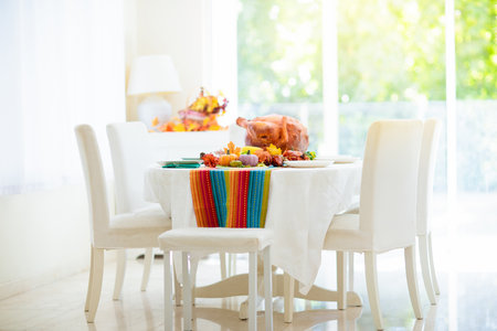 Thanksgiving dinner. Roasted turkey and vegetable meal. Festive home decoration and table setting. Traditional grilled meat, corn and pumpkin for autumn family holiday.の写真素材