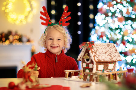 Kids baking Christmas gingerbread house. Children celebrating winter holiday at home. Decorated...