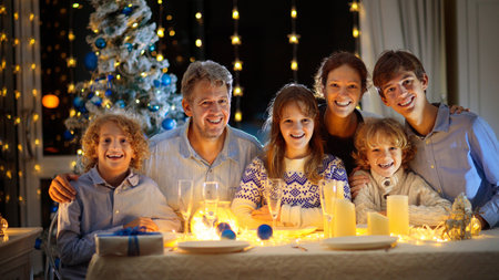 Family with children eating Christmas dinner at fireplace and decorated Xmas tree. Parents and children enjoy festive meal. Winter holidays celebration and food. Father cooking roasted turkey.の写真素材