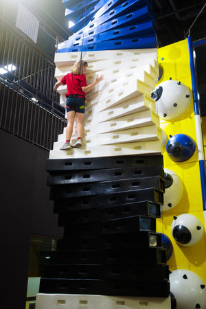 Child climbing in amusement park. Bouldering fun on kids birthday party. Indoor playground with climb wall. Healthy activity for children. Fit kid exercising and playing on colorful rock.の写真素材
